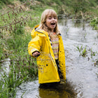 A blonde girl in a stream, wearing a Puddleflex Waterproof Fleece Lined Jacket in yellow. She's smiling and appears to be enjoying herself.